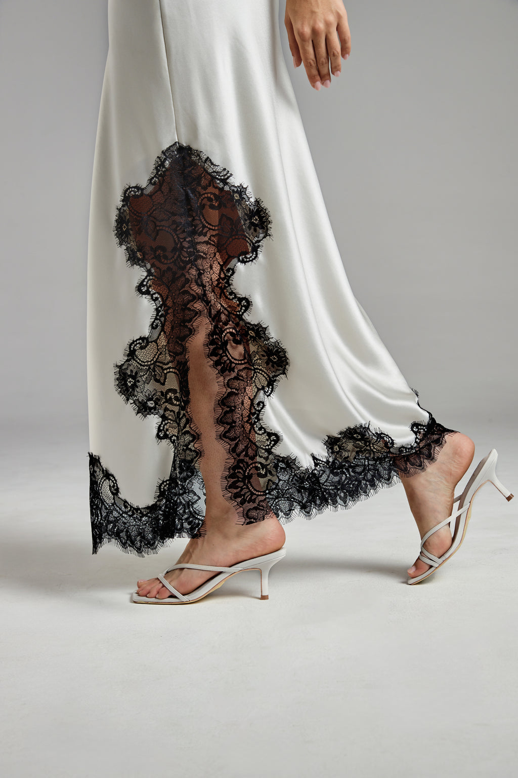 The Anouk Maxi Skirt in Feather White shown close-up with a satin finish and black eyelash-lace trim detail.