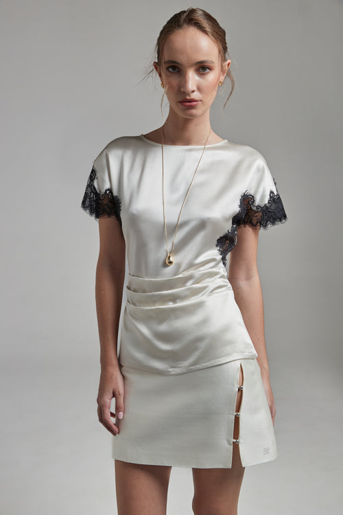 The Anya Mini Skirt in Feather White, a wool silk mini skirt shown from the front with faux-wrap detail, styled with the Paloma Top.