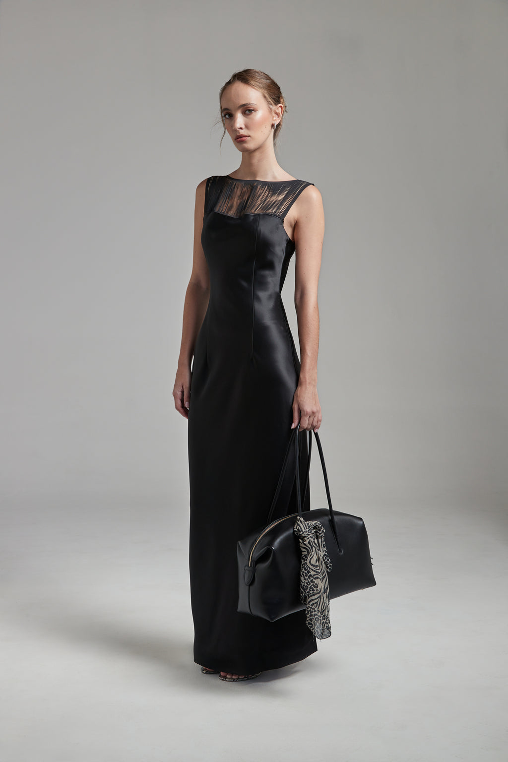 The Carolyn Maxi Dress in Midnight Black shown full-length from the front with a satin finish, fringe detailing and boat neckline.