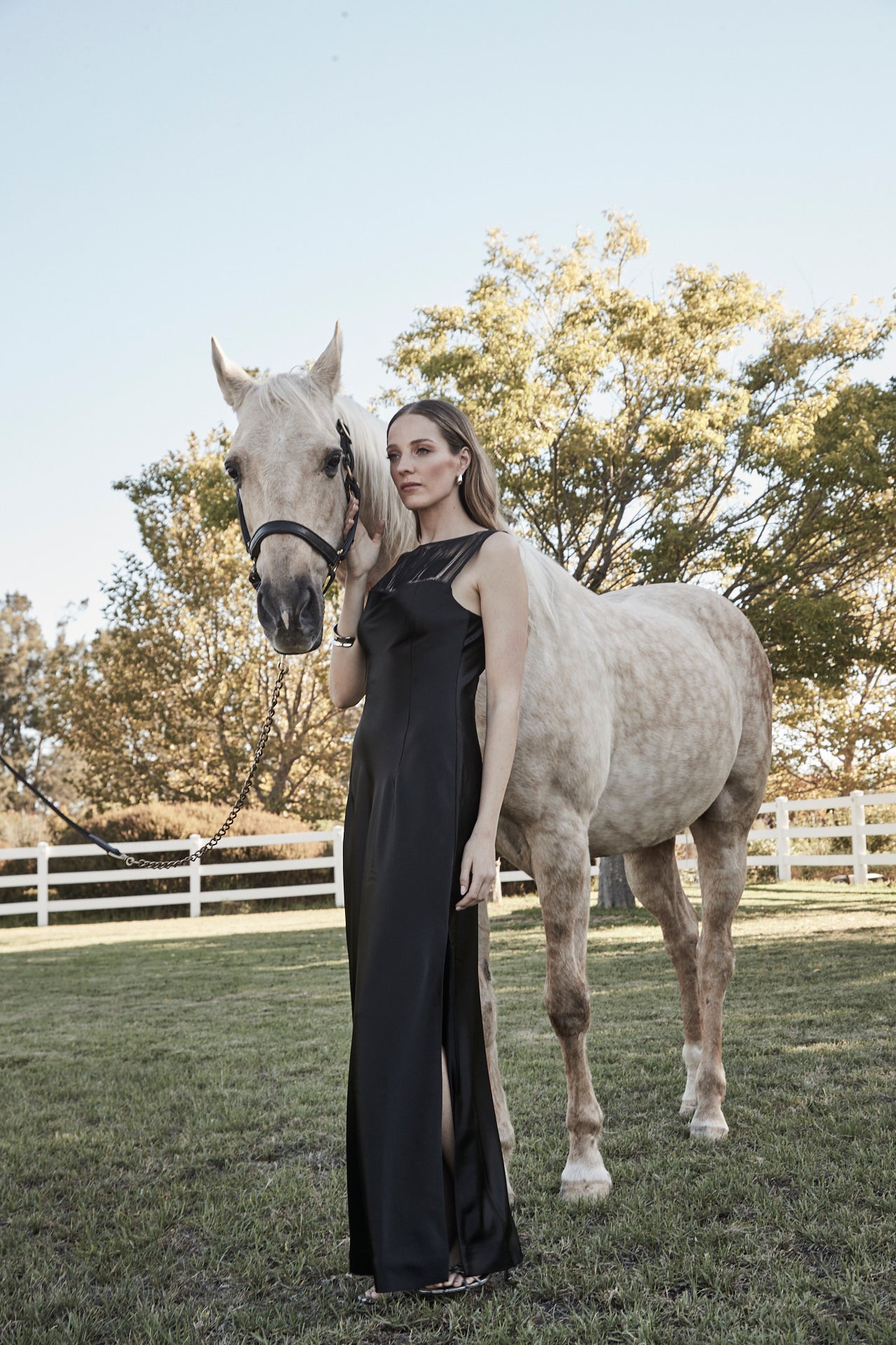 The Carolyn Maxi Dress in Midnight Black, a satin maxi dress with boat neckline, fringe detail and full-length silhouette.
