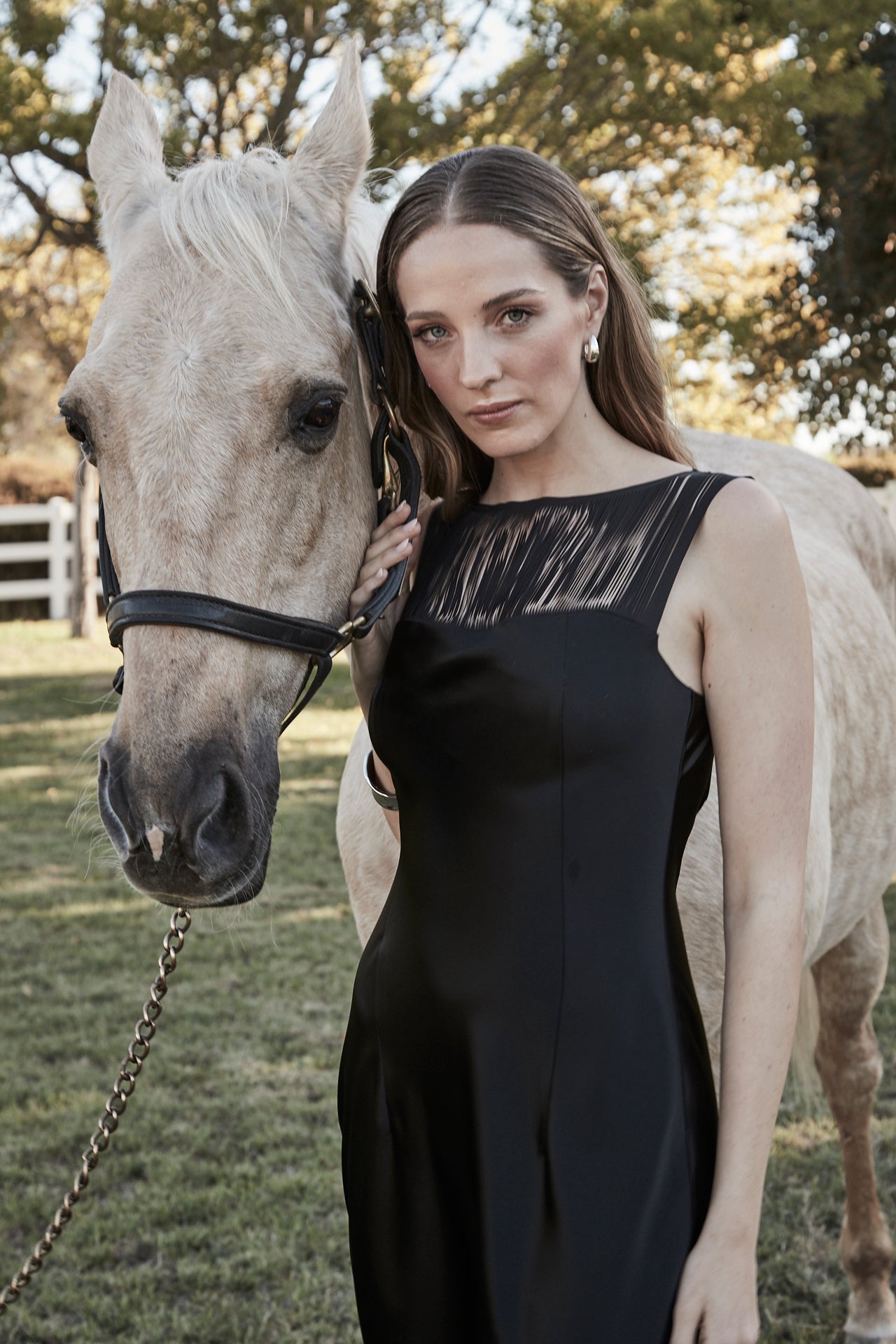 The Carolyn Maxi Dress in Midnight Black, a satin maxi dress with boat neckline and fringe detail shown in a close-up image.