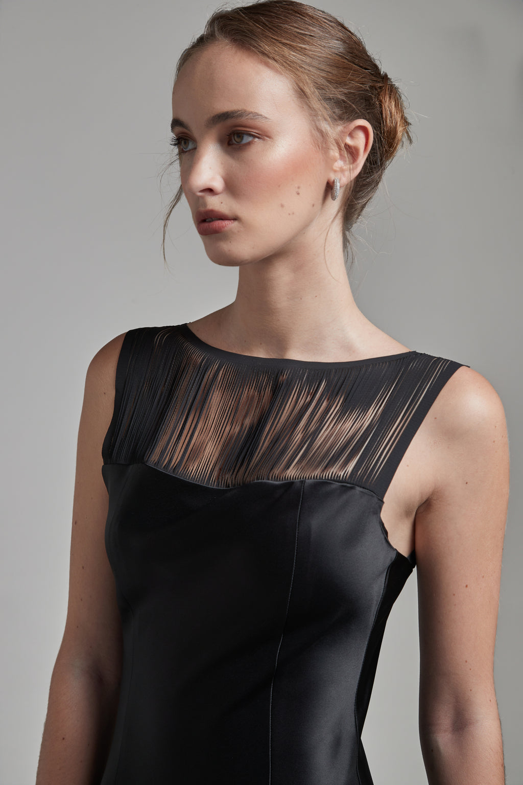 The Carolyn Maxi Dress in Midnight Black shown close-up from the side with a satin finish and fringe detailing.