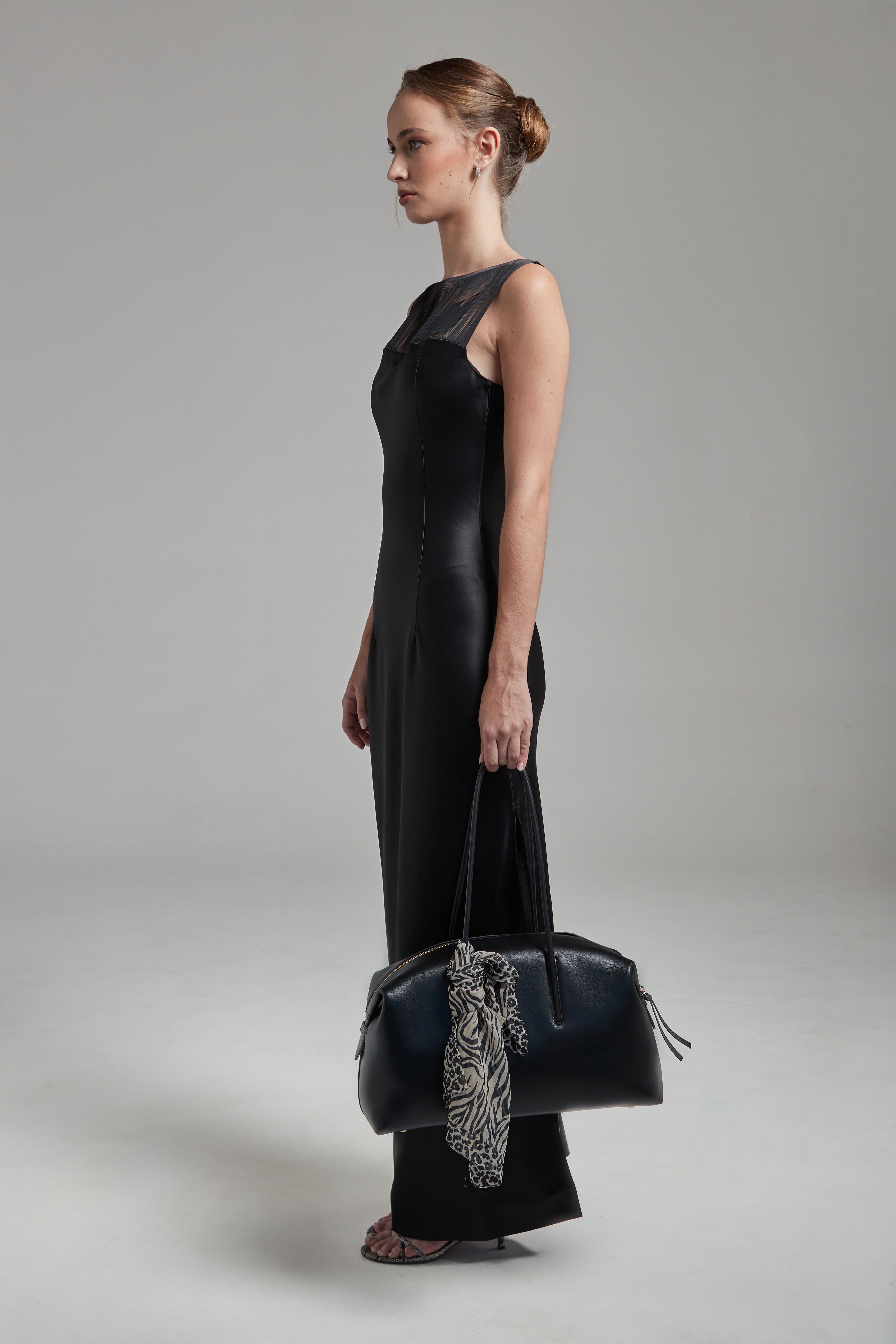 The Carolyn Maxi Dress in Midnight Black shown full-length from the side with a satin finish, fringe detailing and fluid silhouette.