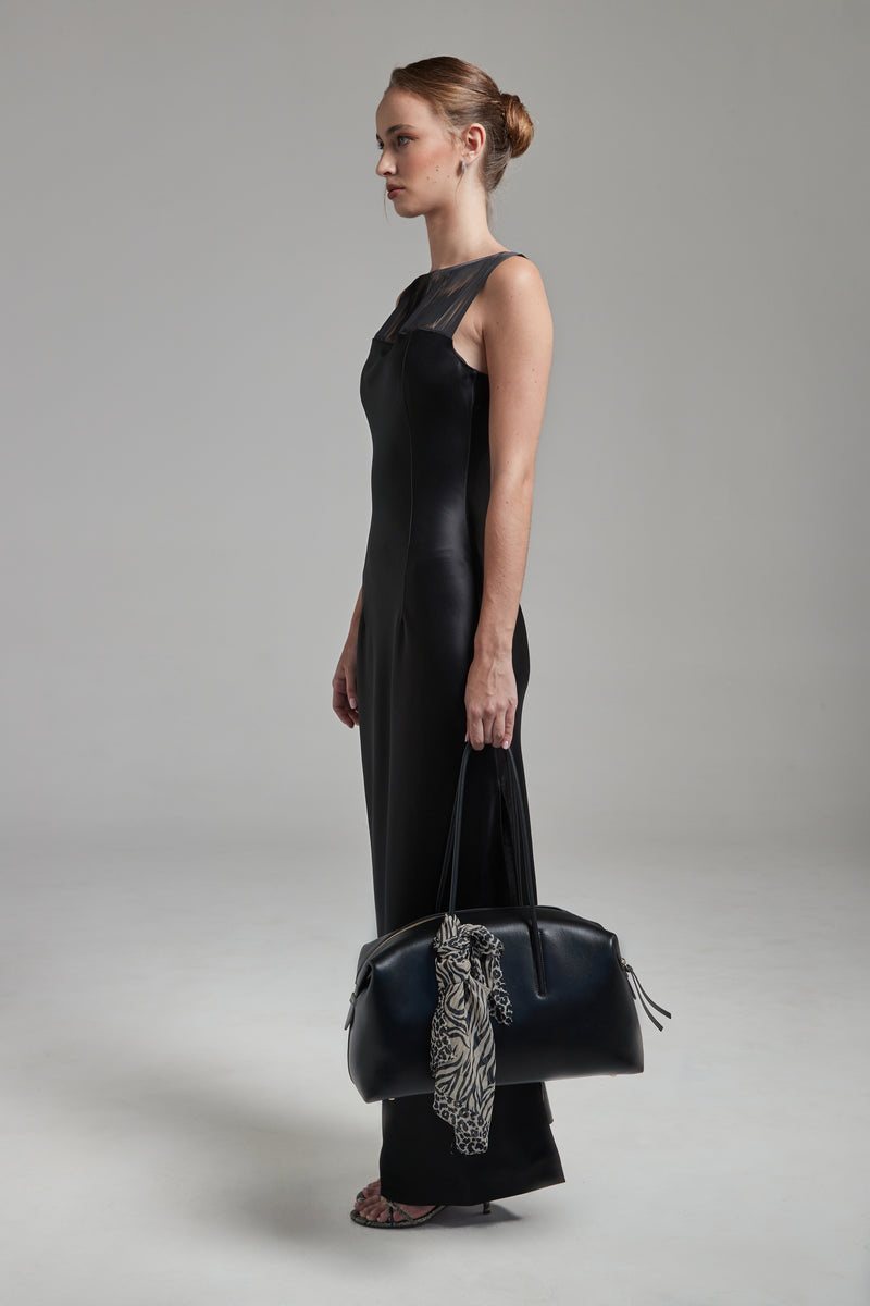 The Carolyn Maxi Dress in Midnight Black shown full-length from the side with a satin finish, fringe detailing and fluid silhouette.