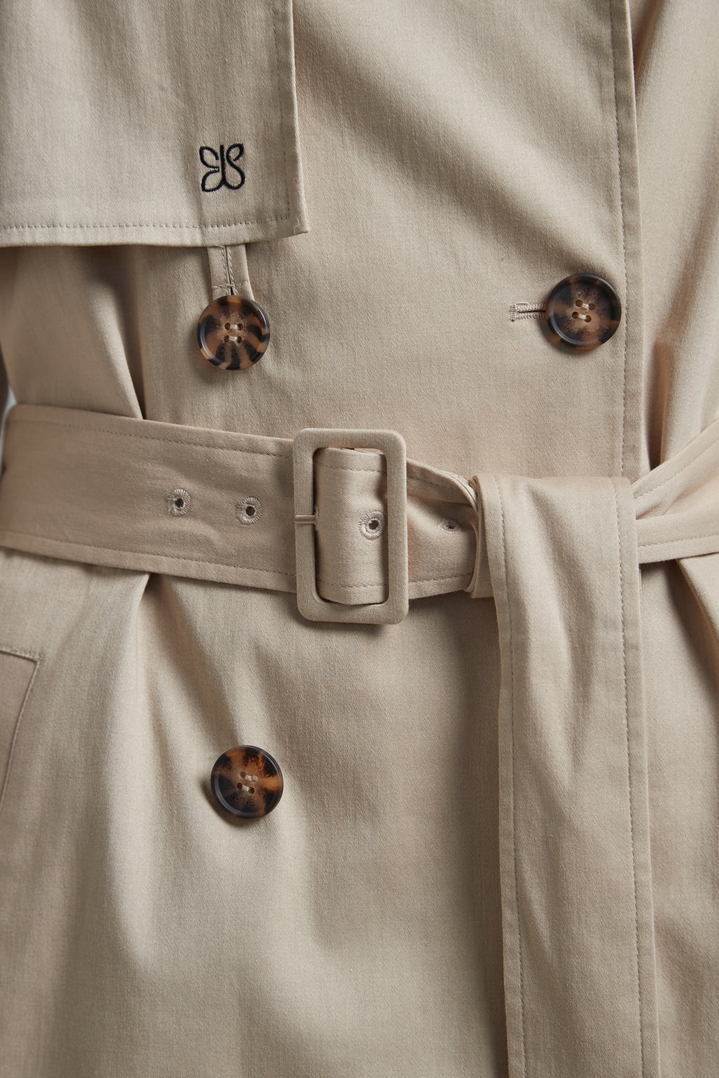 The Celeste Trench Coat in White Pepper shown close-up with a funnel neckline and structured outerwear detailing.