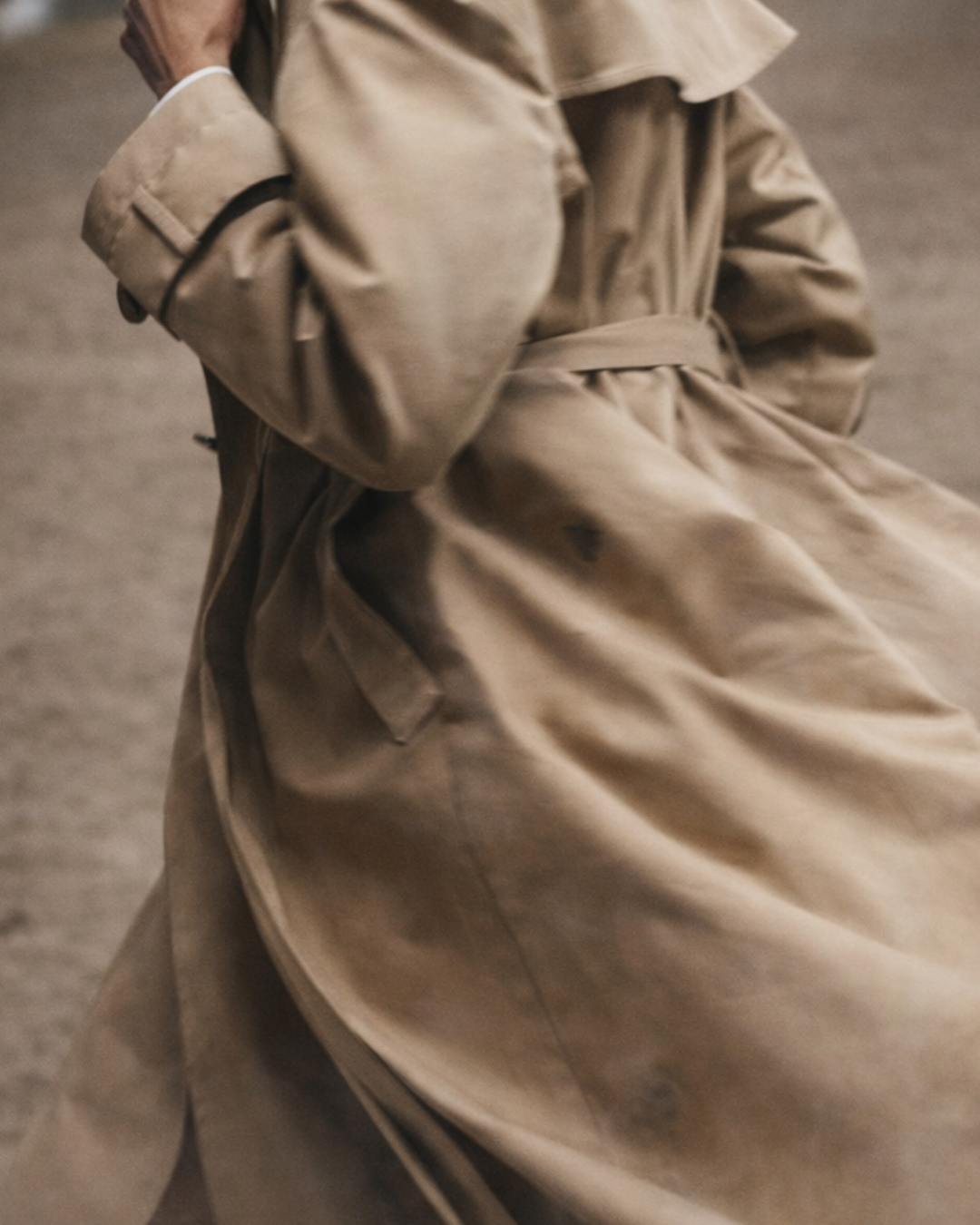 Close-up of a person wearing a beige cotton funnel neck trench coat