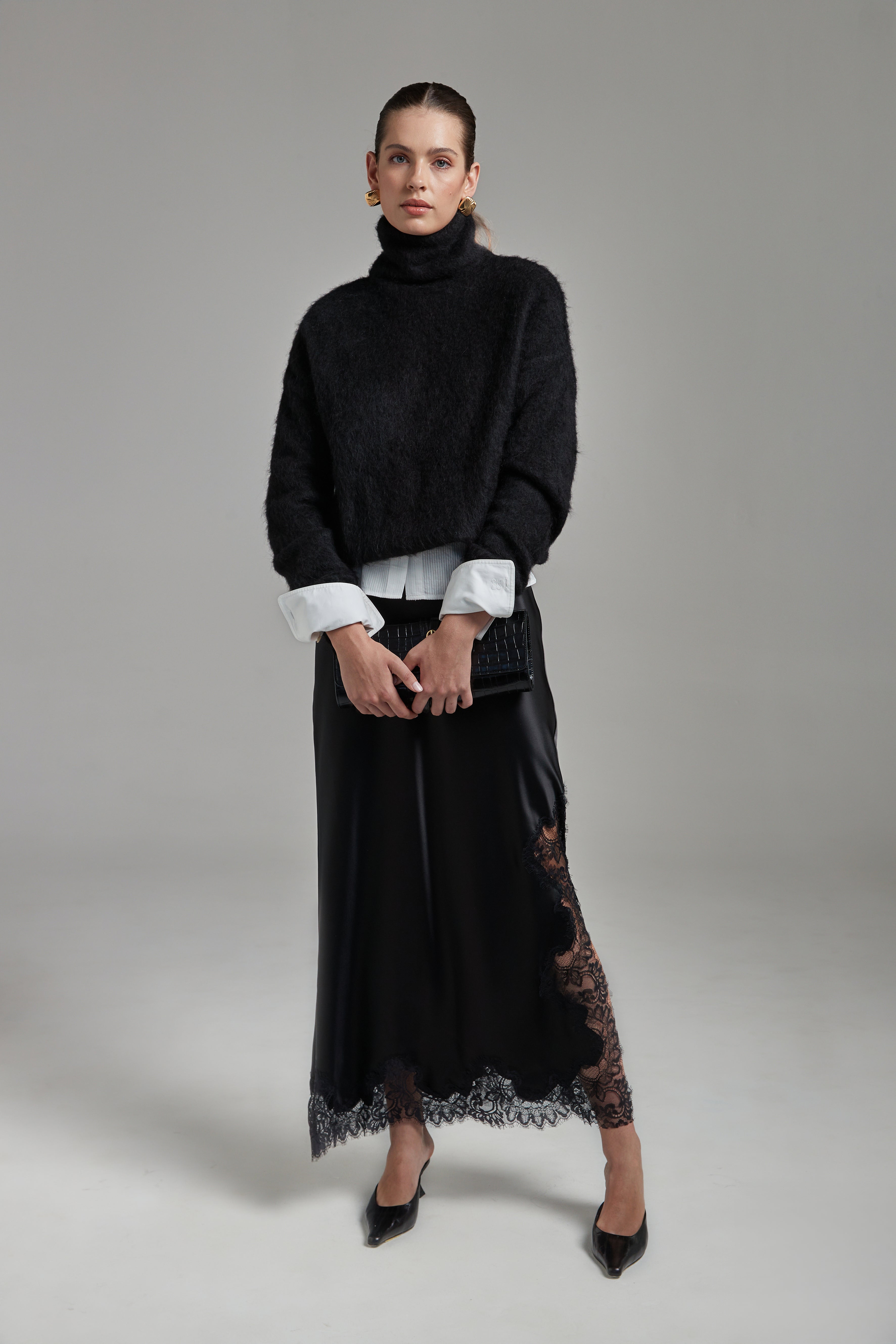 Model wearing the Lauren Turtleneck in Midnight Black layered over the Margot Shirt with the Anouk Maxi Skirt, shown full-length from the front with a brushed alpaca-blend knit and black lace trim.