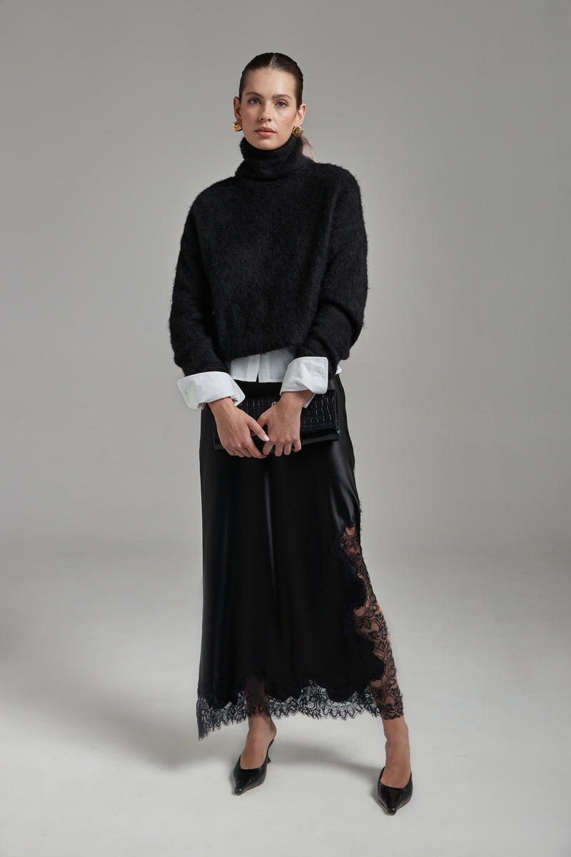 Model wearing the Lauren Turtleneck in Midnight Black layered over the Margot Shirt with the Anouk Maxi Skirt, shown full-length from the front with a brushed alpaca-blend knit and black lace trim.