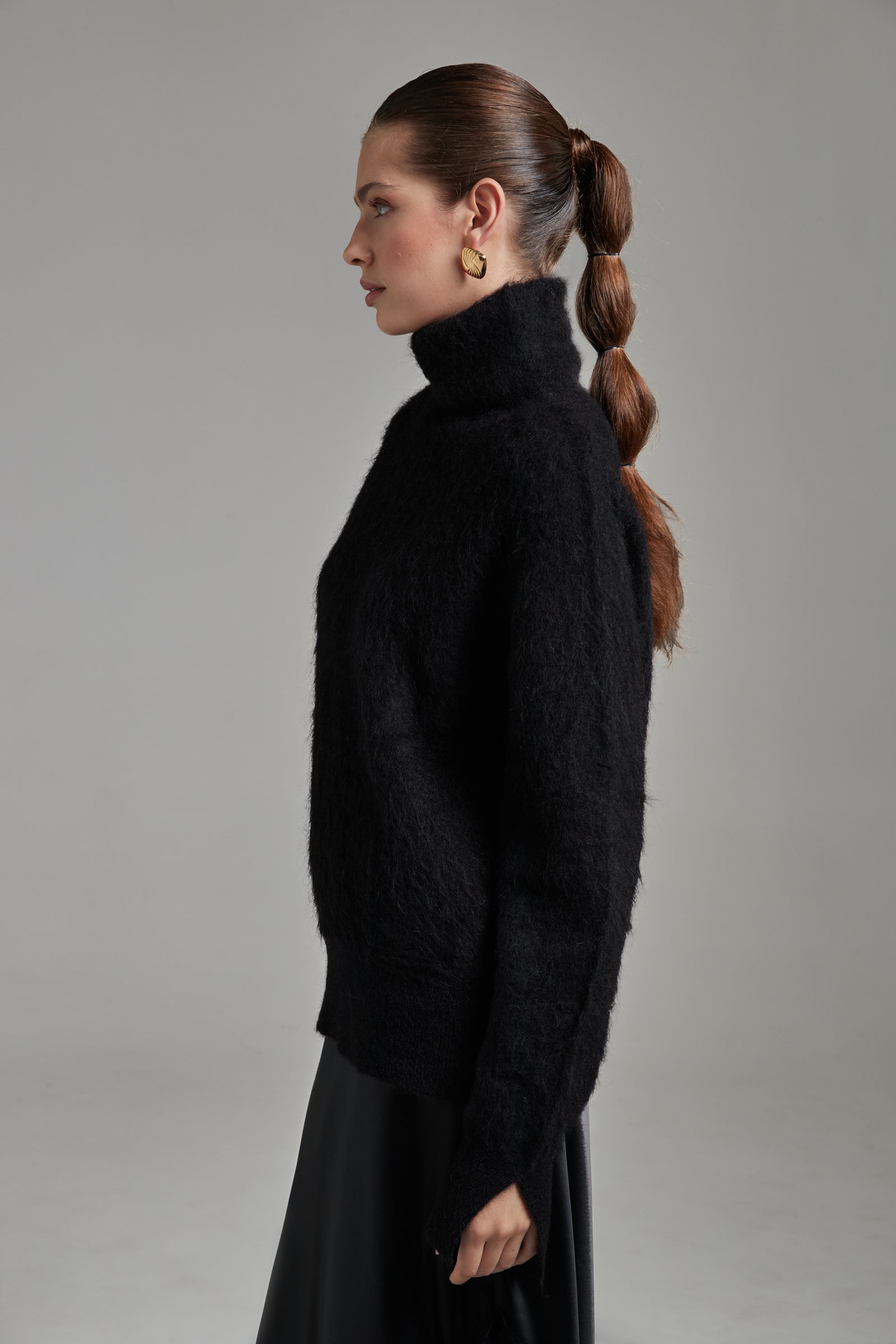 The Lauren Turtleneck in Midnight Black shown from the side with long sleeves, a brushed alpaca-blend texture and soft stretch.