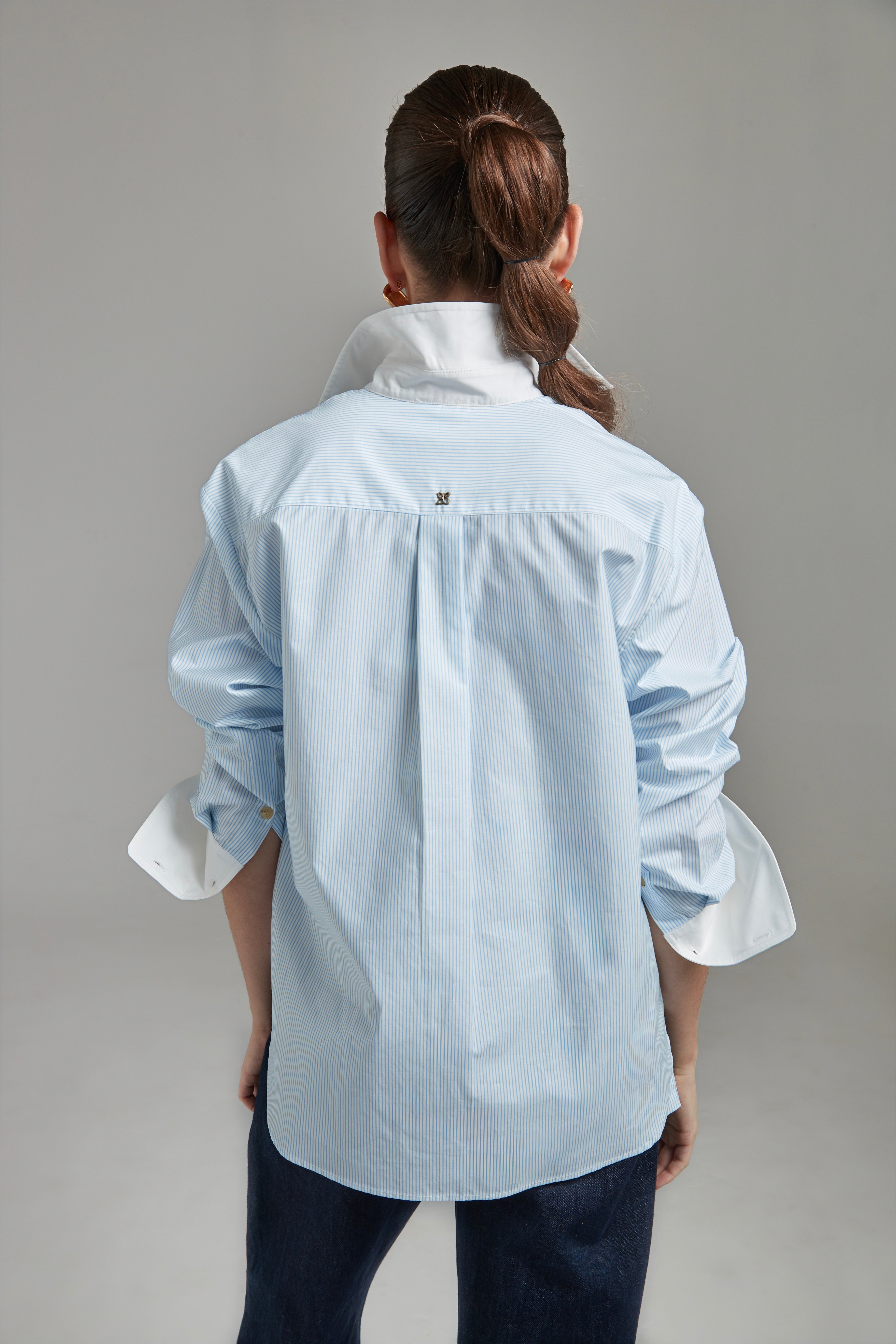 he Margot Shirt – All Tied Up in Blue/White Pinstripe shown from the back with logo hardware detailing and fine pinstripe cotton shirting.
