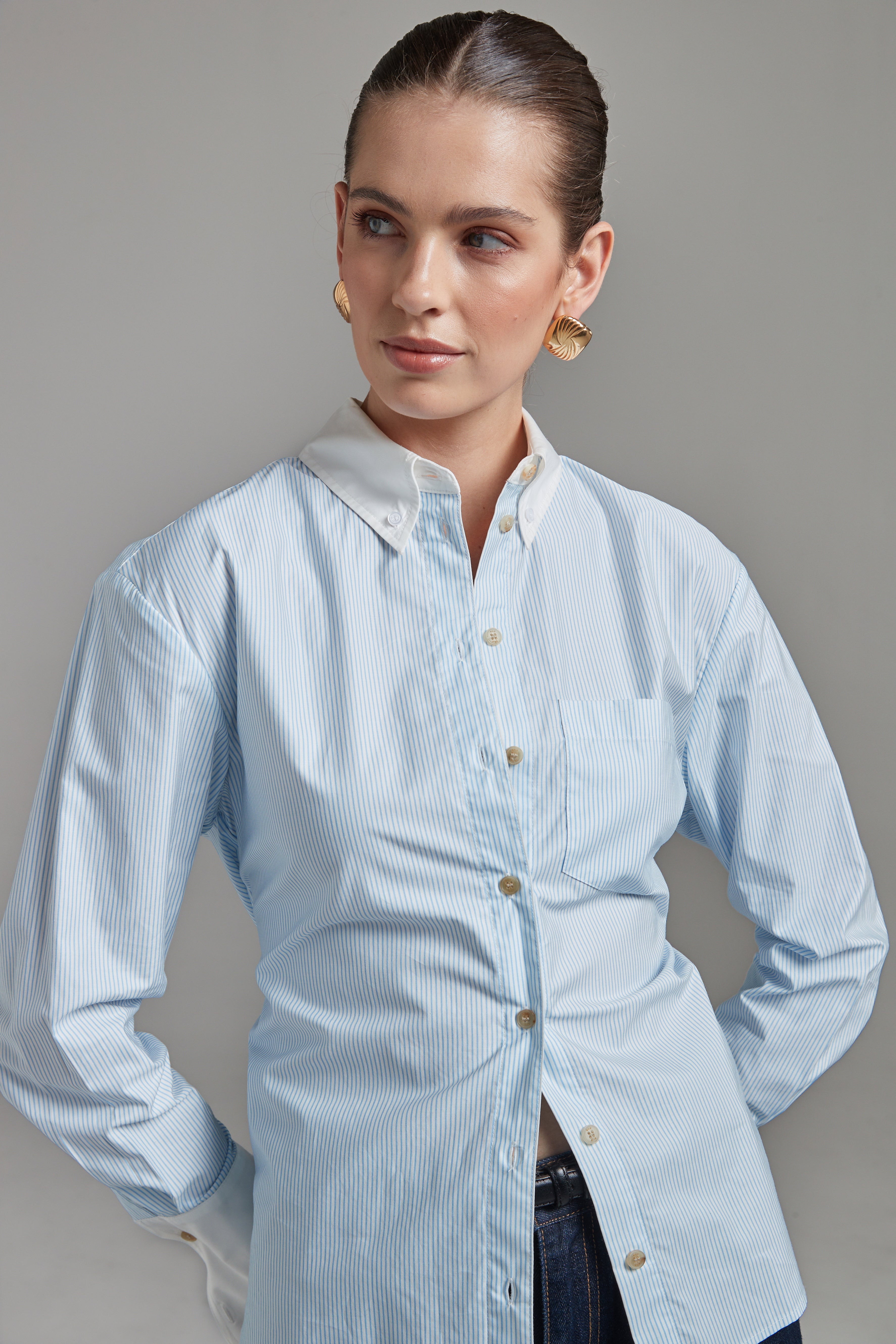 The Margot Shirt – All Tied Up in Blue/White Pinstripe shown close-up from the front with a cinched waist, contrast collar and cotton shirting detail.