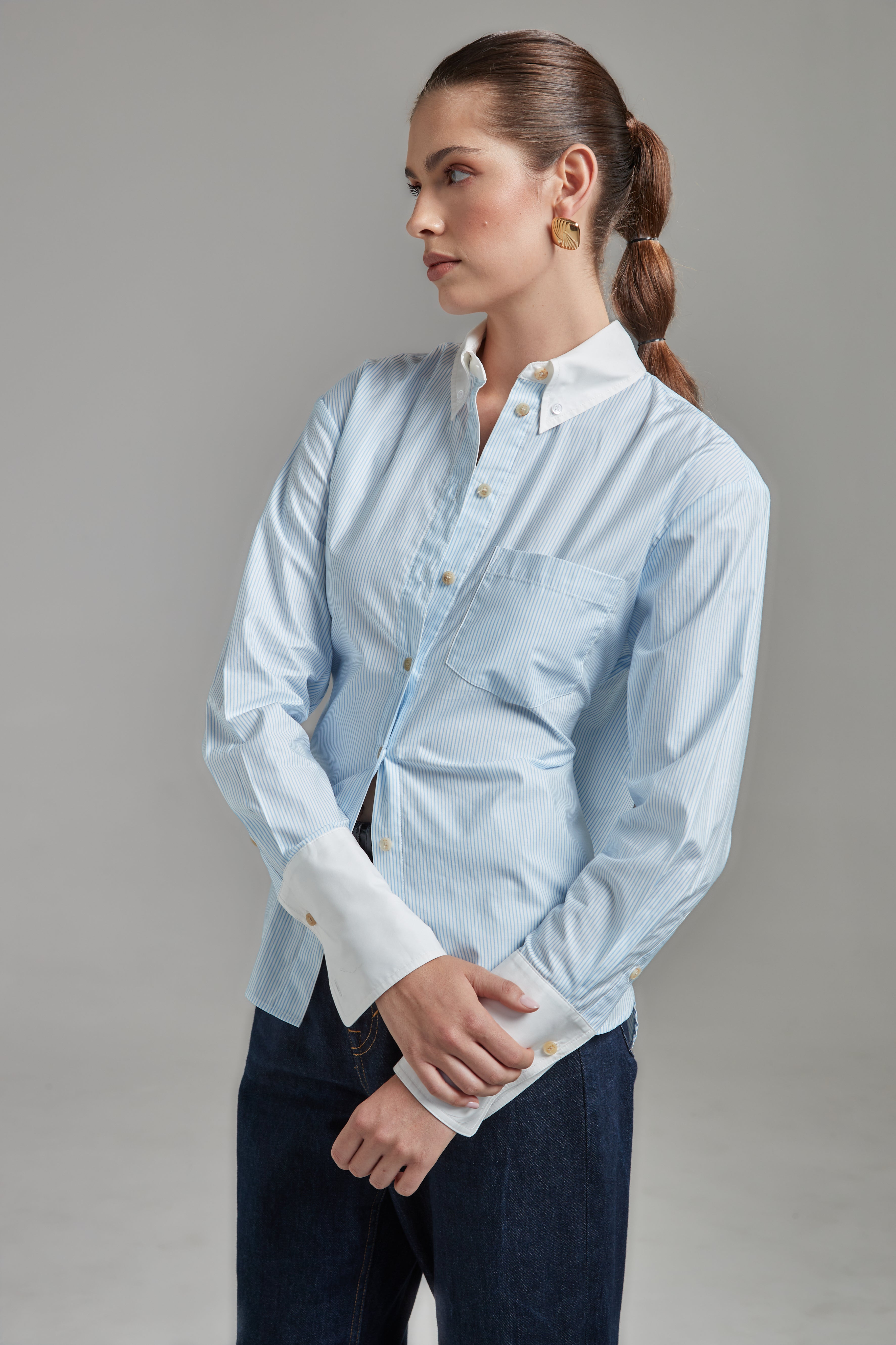 The Margot Shirt – All Tied Up in Blue/White Pinstripe, a cotton button-down shirt shown close-up with exaggerated cuffs and pinstripe detail.