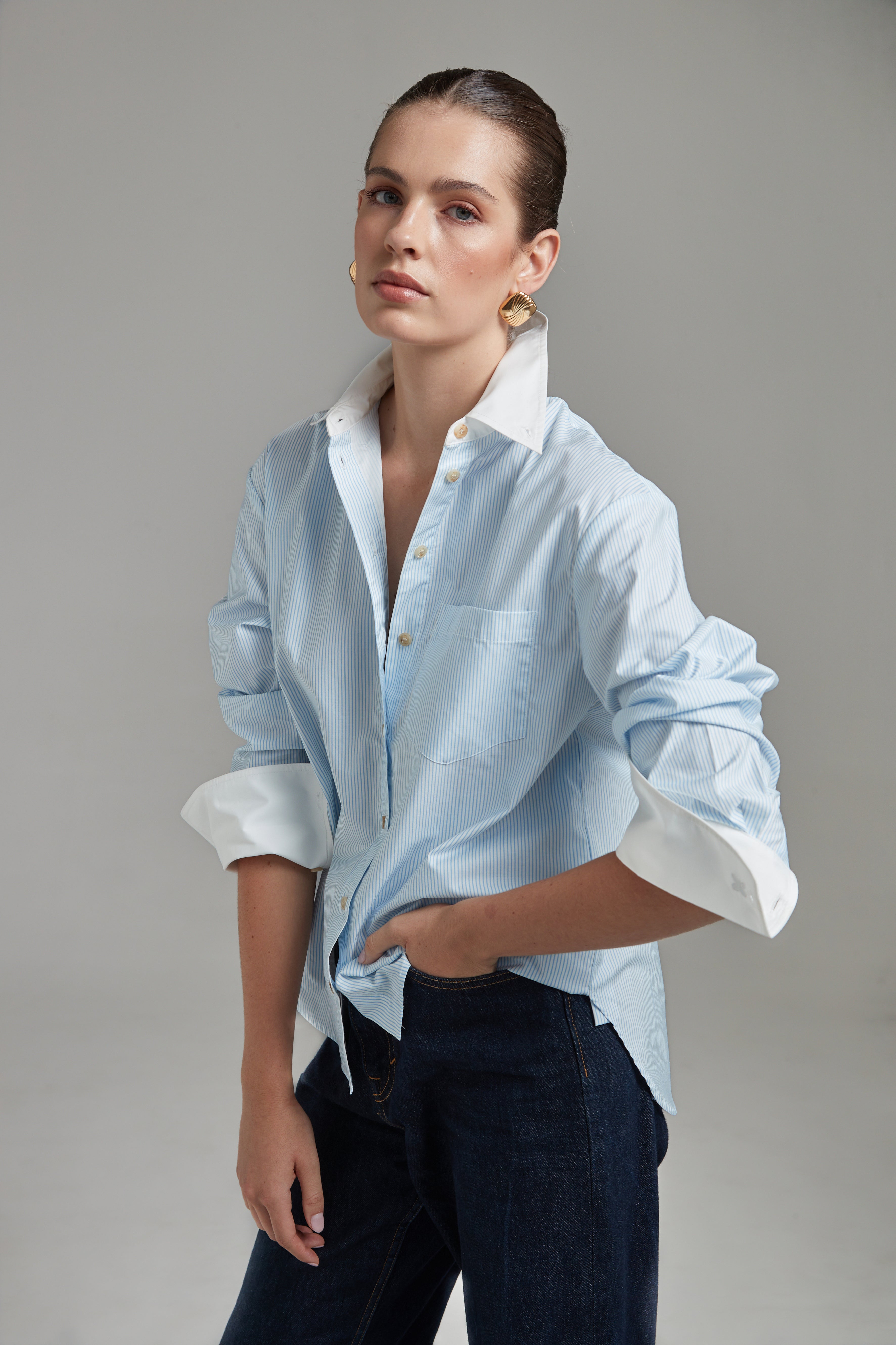 The Margot Shirt – All Tied Up in Blue/White Pinstripe shown from the side with rolled cuffs, contrast collar and fine pinstripe cotton shirting.