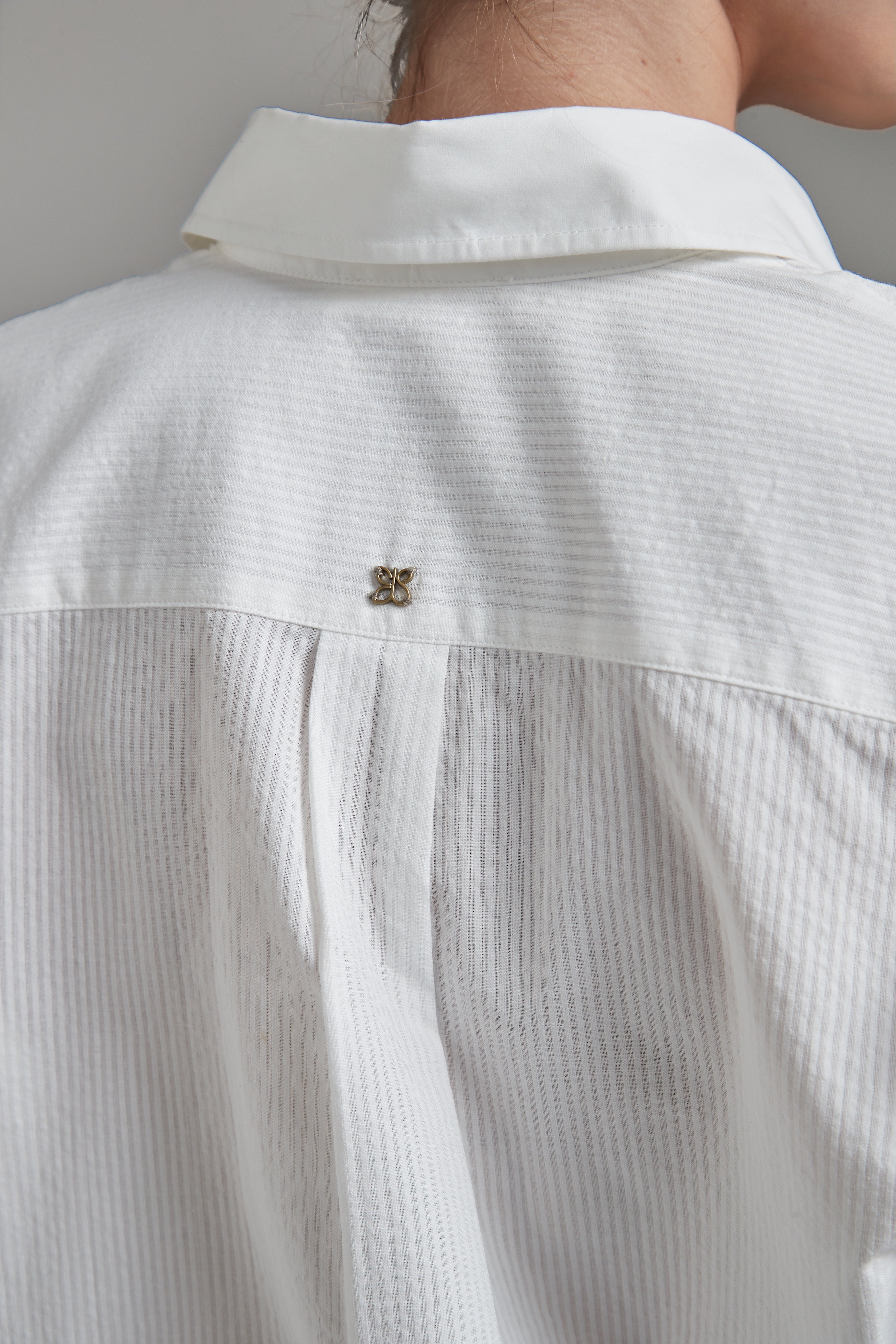 The Margot Shirt in Cloud White shown close-up from the back with tonal cotton shirting and logo hardware detail.
