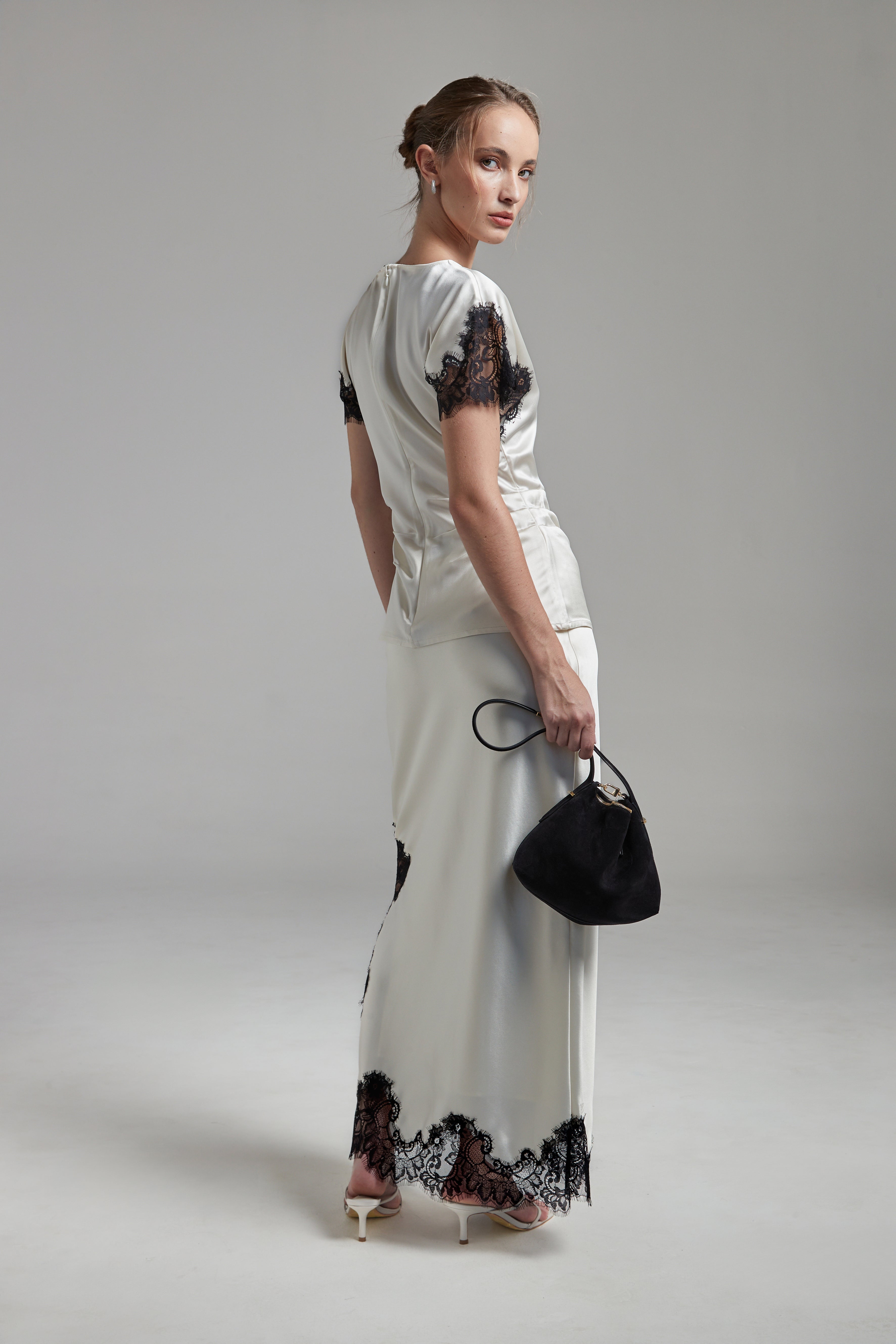 The Paloma Top in Feather White shown full-length from the back with a satin finish, black lace panel detailing and a fitted silhouette.