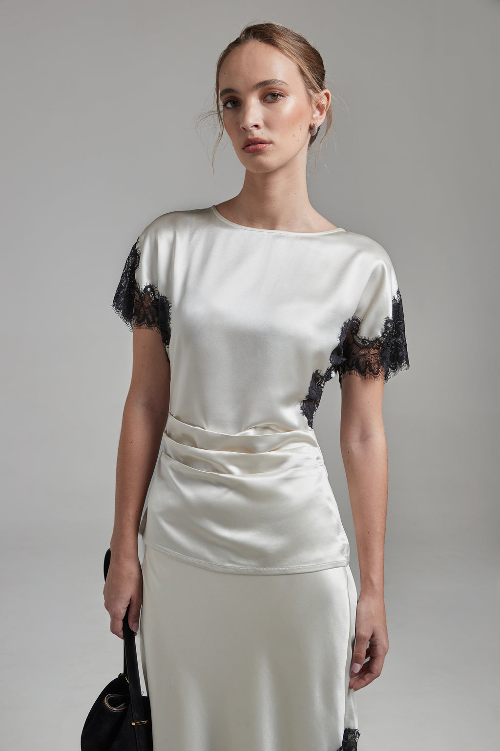 The Paloma Top in Feather White shown full-length from the front with pleated satin detailing and contrast black lace trim.