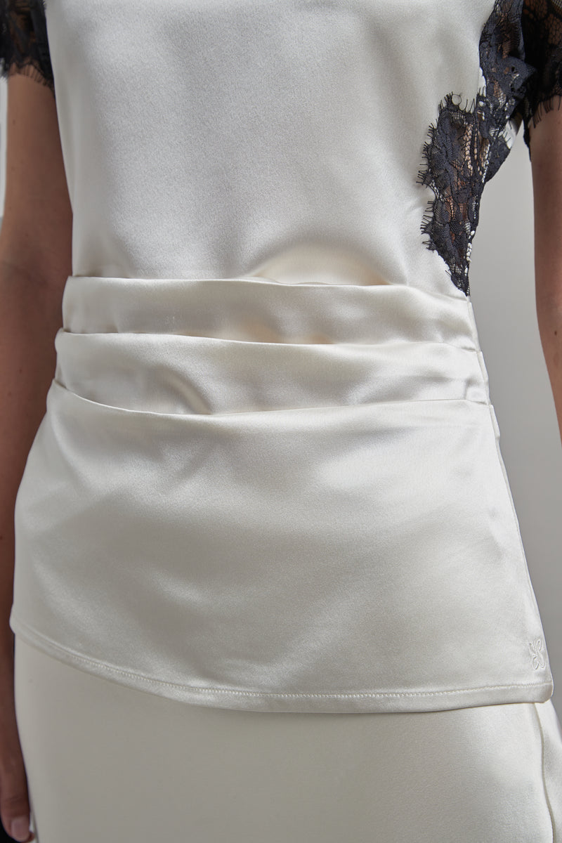 The Paloma Top in Feather White, a satin lace panel top shown close-up with pleat detail and black lace detailing.