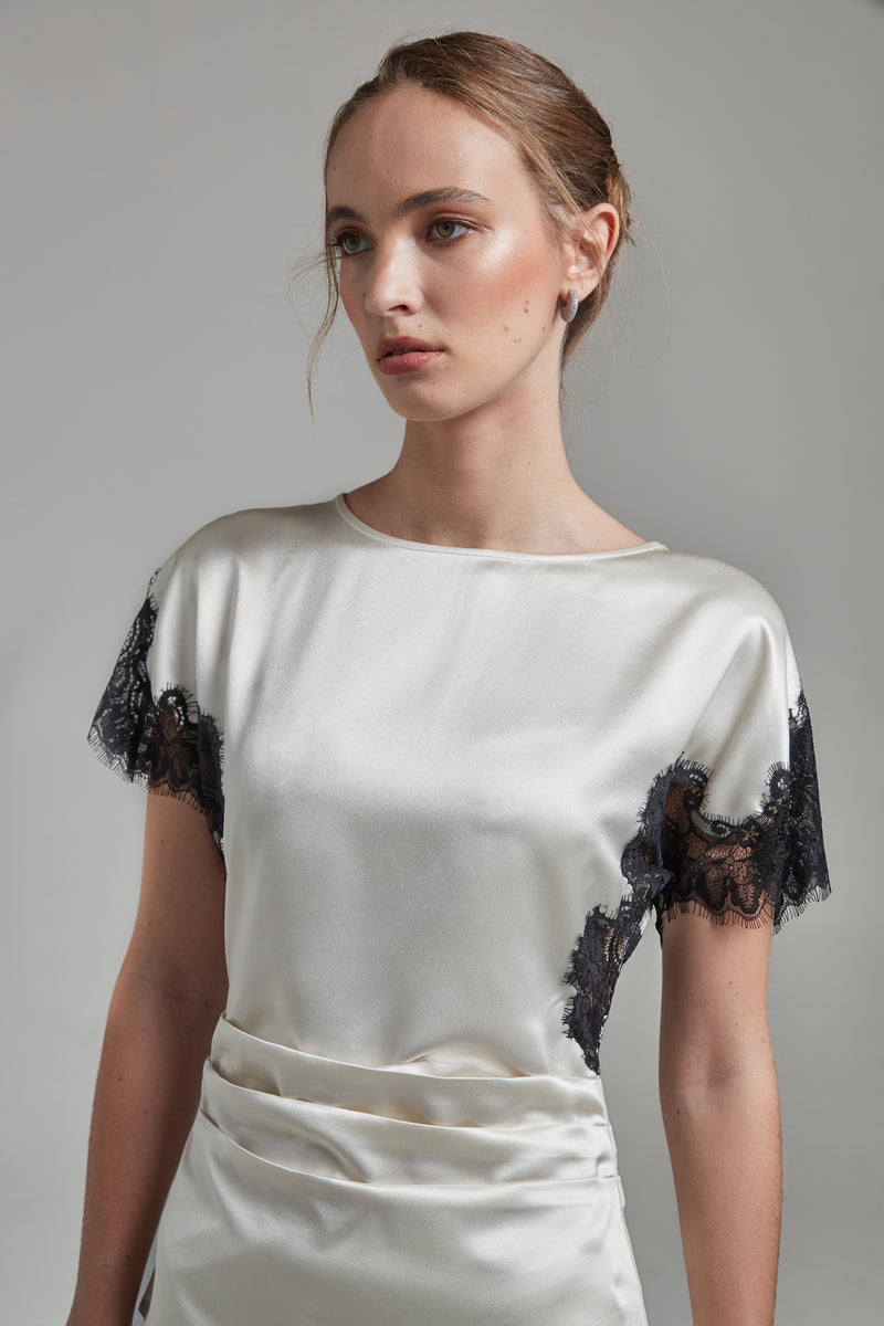 The Paloma Top in Feather White shown close-up from the side with a satin finish, black lace panel detailing and a fitted silhouette.