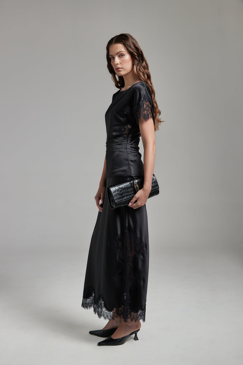 Model wearing the Paloma Top in Midnight Black with the Anouk Maxi Skirt, shown full-length from the side with tonal lace detailing and a fluid silhouette.