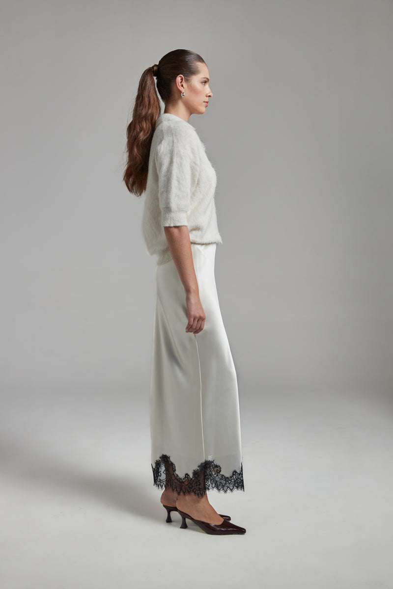 Model wearing the Stella Polo Knit and Anouk Maxi Skirt in Feather White, featuring an alpaca-blend knit and satin skirt with black lace trim.