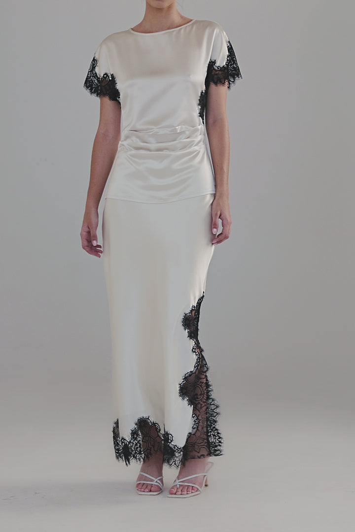 Video showing the Anouk Maxi Skirt in Feather White with close-up details of the satin finish, black lace trim and ankle-length silhouette.